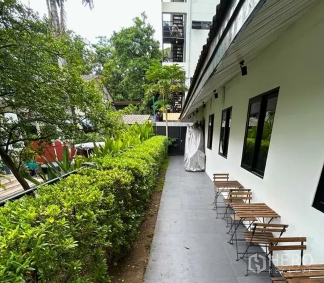 Retail Space for rent in Yan Nawa, Bangkok - Side terrace with hedge, outdoor seating and walkway beside a white facade.