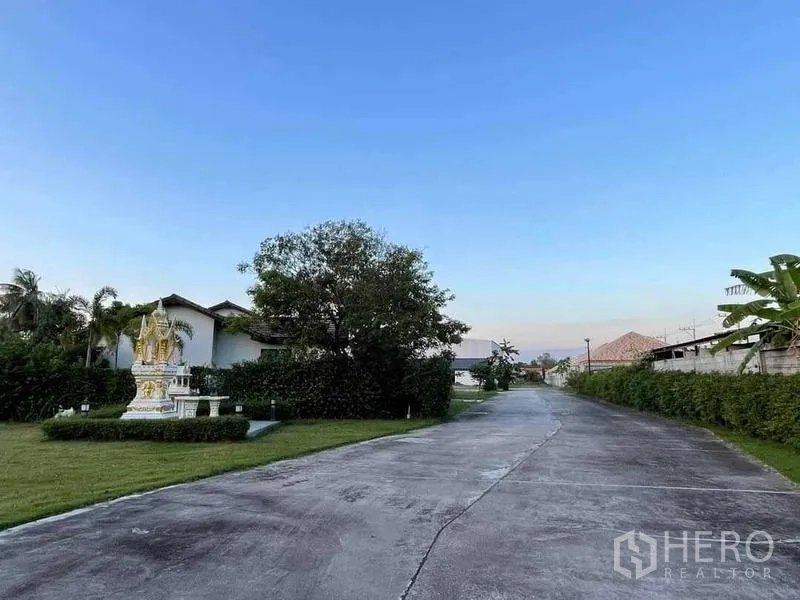 Warehouse for sale in Chon Buri - Internal concrete road lined with hedges and a landscaped spirit-house garden inside the compound.