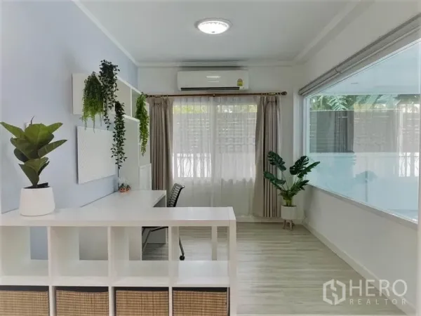 独立式住宅 出租在Suan Luang, Bangkok - 采光充足的书房角，配书桌、置物架、空调与绿植。