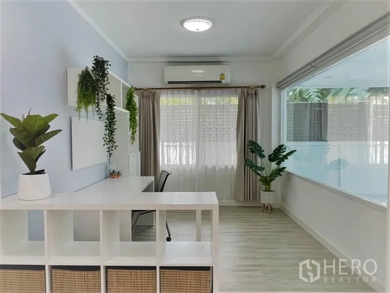 独立式住宅 出租在Suan Luang, Bangkok - 采光充足的书房角，配书桌、置物架、空调与绿植。