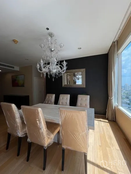 Condominium for rent in Watthana, Bangkok - Dining area with six chairs and crystal chandelier beside a city-view window.