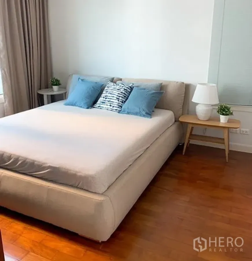 Condominium for rent in Khlong Toei, Bangkok - Bright bedroom with a king-size bed, side tables and wooden flooring.