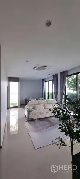 独立式住宅 出租在Lat Krabang, Bangkok - 宽敞客厅，落地窗、沙发与花园景观，曼谷独栋出租屋。