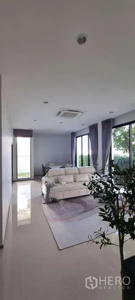 独立式住宅 出租在Lat Krabang, Bangkok - 宽敞客厅，落地窗、沙发与花园景观，曼谷独栋出租屋。