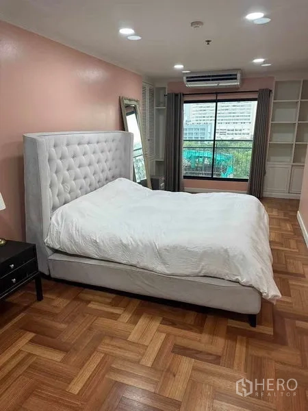 Condominium for sale in Bangkok - Master bedroom with large window, built-in shelving, air conditioner and city outlook.