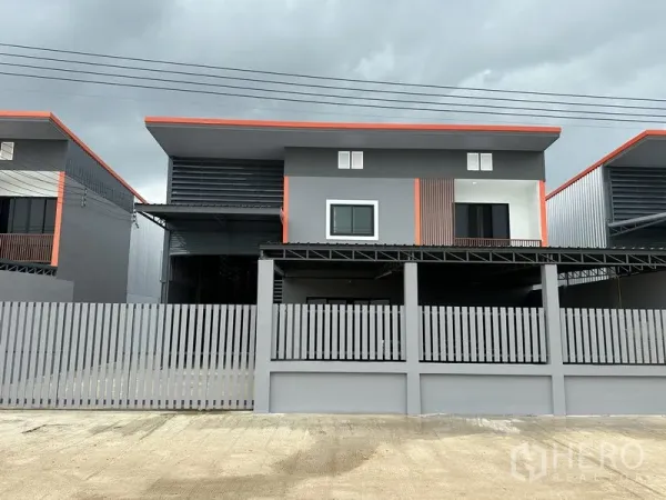 货栈 出租在Lam Luk Ka, Pathum Thani - 现代两层仓库外观，灰色外立面配橙色线条与围栏大门