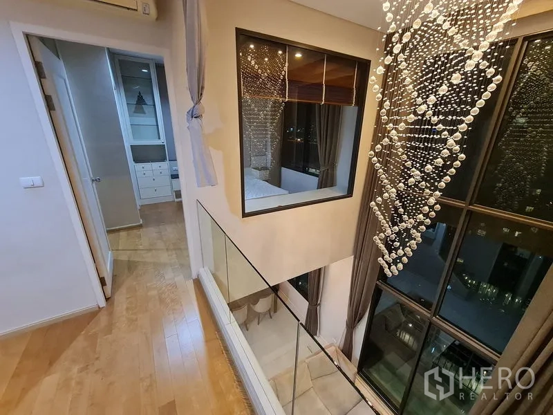 公寓 出售在Ratchathewi, Bangkok - 夹层走道，玻璃栏杆与闪耀水晶吊饰俯瞰客厅