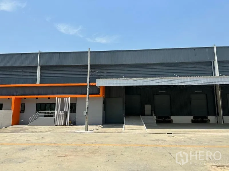 Warehouse for rent in Bang Phli, Samut Prakan - Modern warehouse exterior with covered dock‑high loading bays and ramp access.