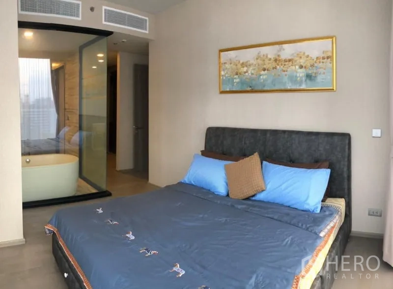 公寓 出租在Watthana, Bangkok - 主卧温馨，蓝色床品，玻璃隔断浴室与独立浴缸。