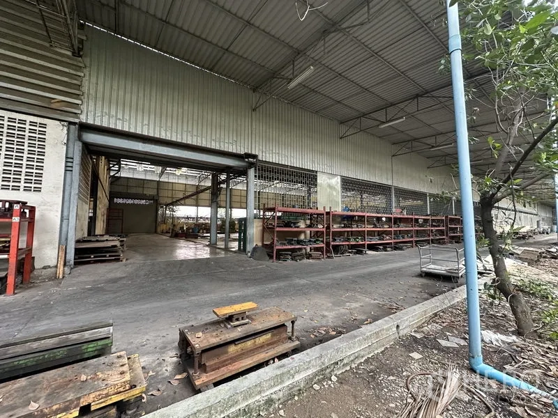 Factory for rent or sale in Lam Luk Ka, Pathum Thani - Exterior covered aisle with racks and a sliding door into the factory.
