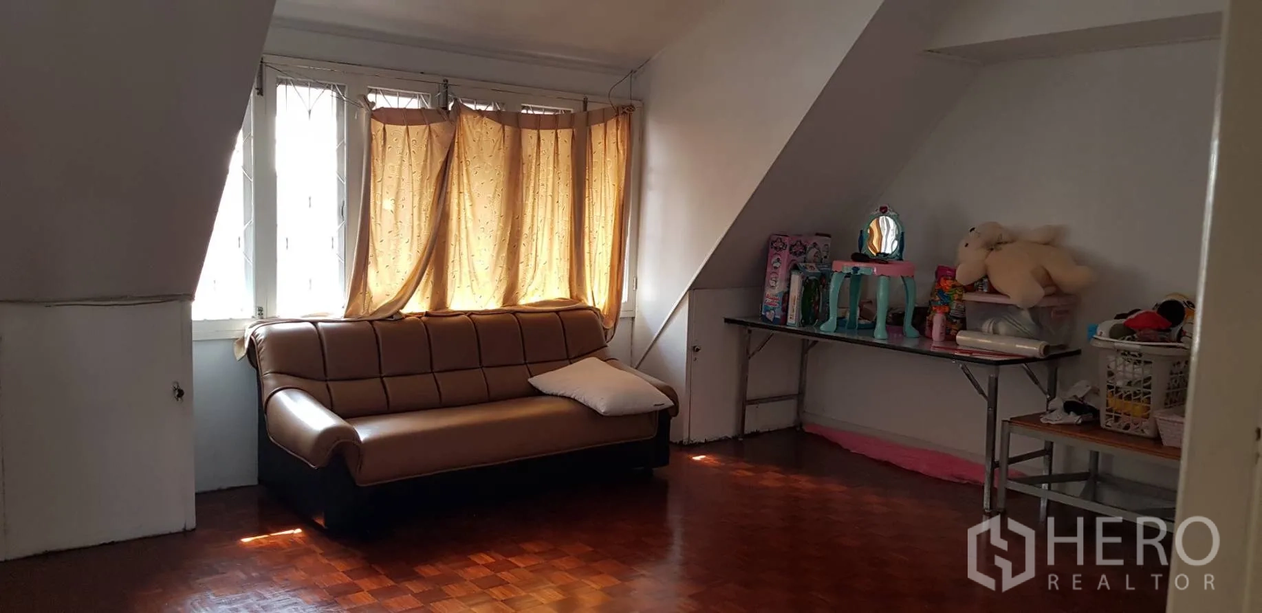 联排别墅 出租在Khlong Toei, Bangkok - 楼上起居角，沙发、拼花木地板与斜顶窗户。