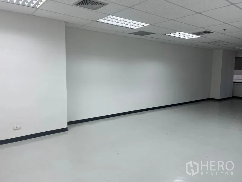 办公空间 出租 - 空置办公区，白色墙面，格栅吊顶与日光灯。