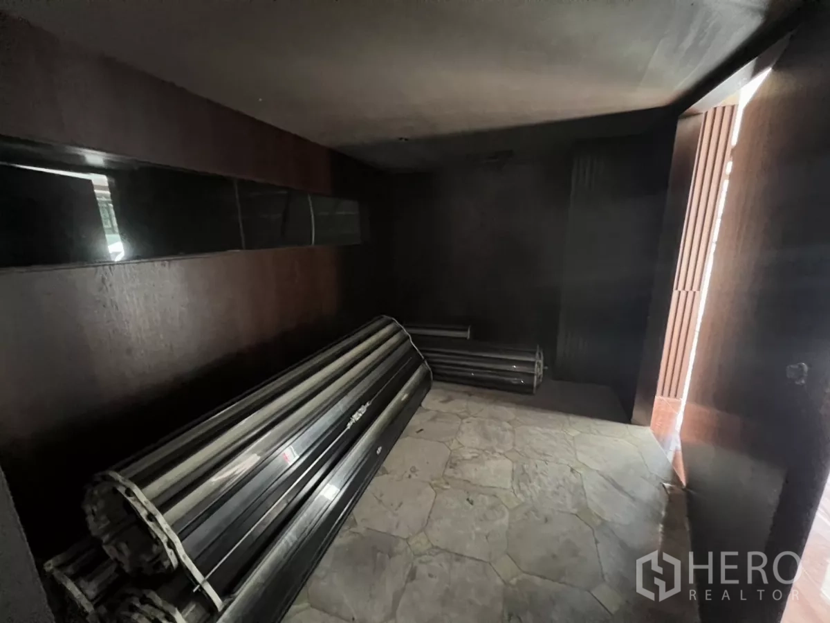 Retail Space for rent in Khlong Toei, Bangkok - Small storage or entry room with stacked metal roller panels on stone flooring.