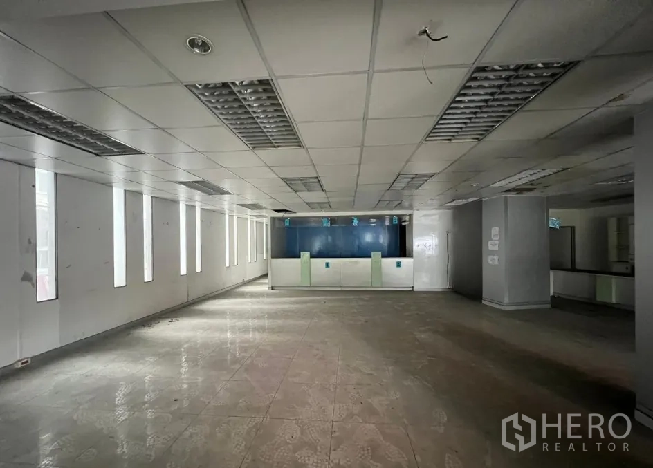 Shophouse for rent or sale in Khlong Toei, Bangkok - Large ground-floor retail space with drop ceiling, tiled floors, and a front service counter.