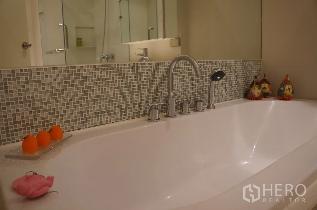 Condominium for rent in Ratchathewi, Bangkok - Bathroom with large soaking bathtub, mosaic tile backsplash and chrome fixtures.