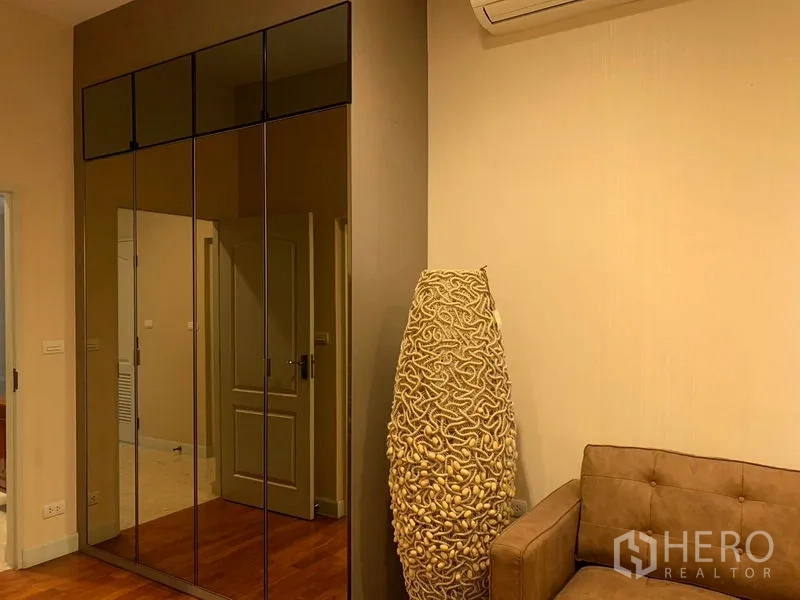 独立式住宅 出租或出售在Khan Na Yao, Bangkok - 室内一角，镜面衣柜、米色沙发与艺术落地灯。