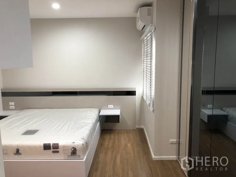 Detached House for rent in Prawet, Bangkok - Cozy bedroom with built-in side tables, air conditioner and wood floors.