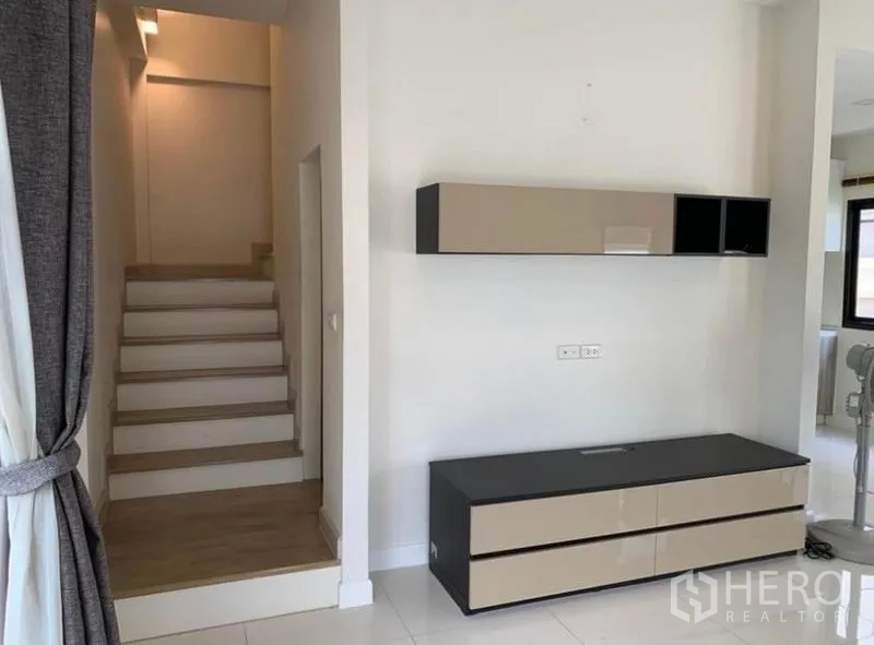 Townhouse for rent in Saphan Sung, Bangkok - Staircase hall with wall-mounted cabinet and TV console in neutral tones, lit by natural light.