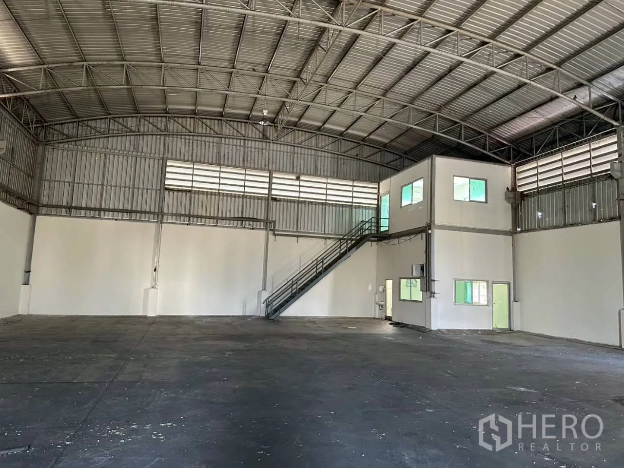 Factory for rent in Lat Lum Kaeo, Pathum Thani - Wide shot of warehouse interior with arched roof trusses and integrated office rooms.