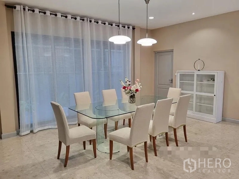 Detached House for rent in Bang Khae, Bangkok - Dining room with glass table for six, pendant lights and sheer curtains.