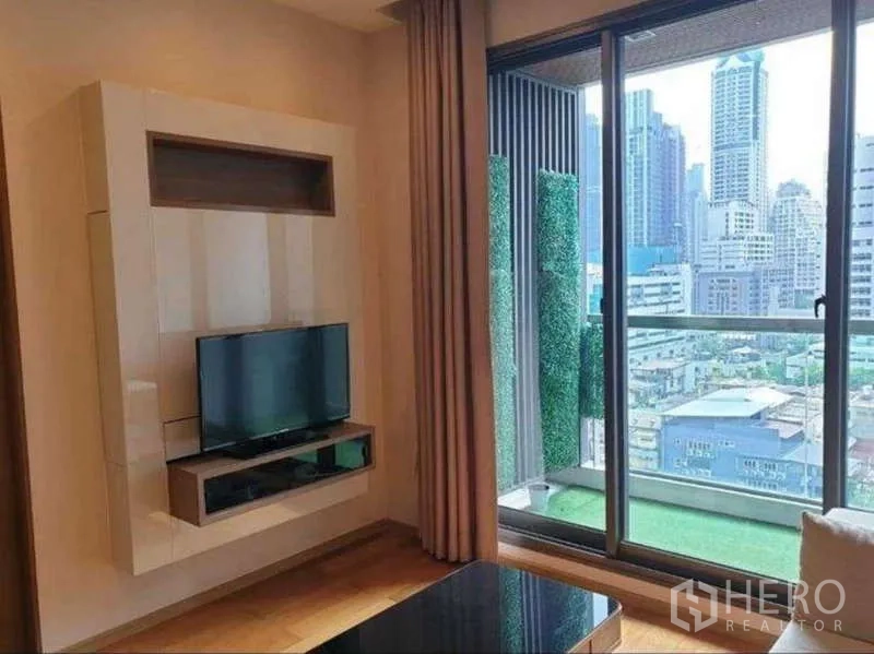 公寓 出租在Bang Rak, Bangkok - 电视背景墙对面是铺人工草坪的阳台，高层远眺城市景观。