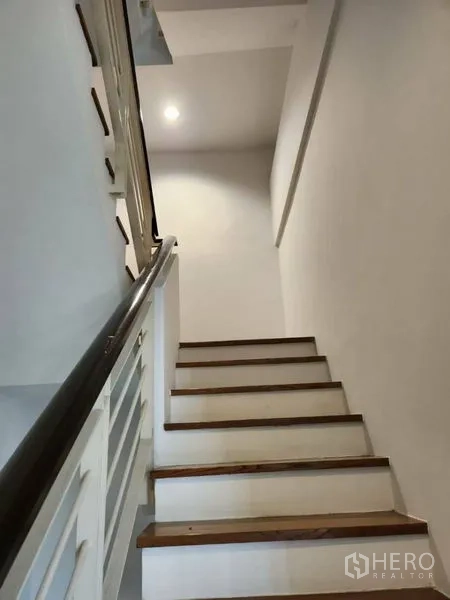 联排别墅 出租或出售在Wang Thonglang, Bangkok - 室内楼梯，木质台阶与白色扶手通向上层。