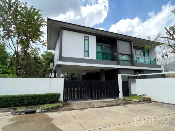 Detached House for rent or sale in Bang Kapi, Bangkok - Modern two-storey detached house with black gate and driveway in Bang Kapi under blue skies.