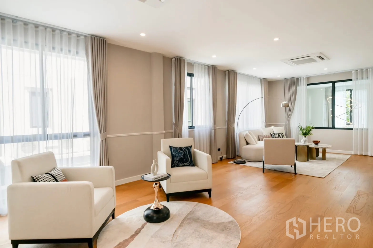 Detached House for rent or sale in Saphan Sung, Bangkok - Spacious living room with white armchairs, sofa set and wood floors.