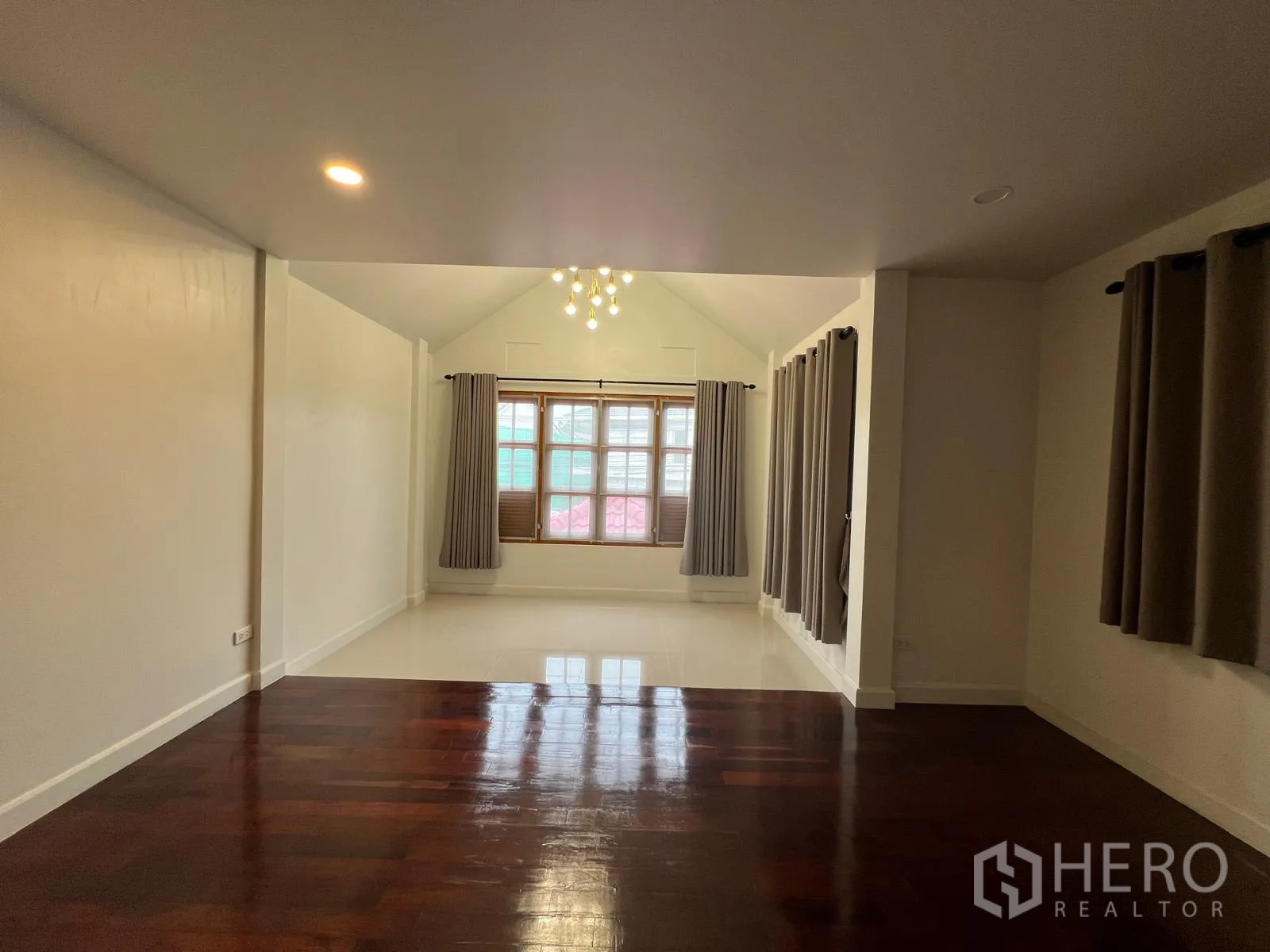 Detached House for rent in Saphan Sung, Bangkok - Open room view with glossy hardwood flooring transitioning to a bright bay area with windows.