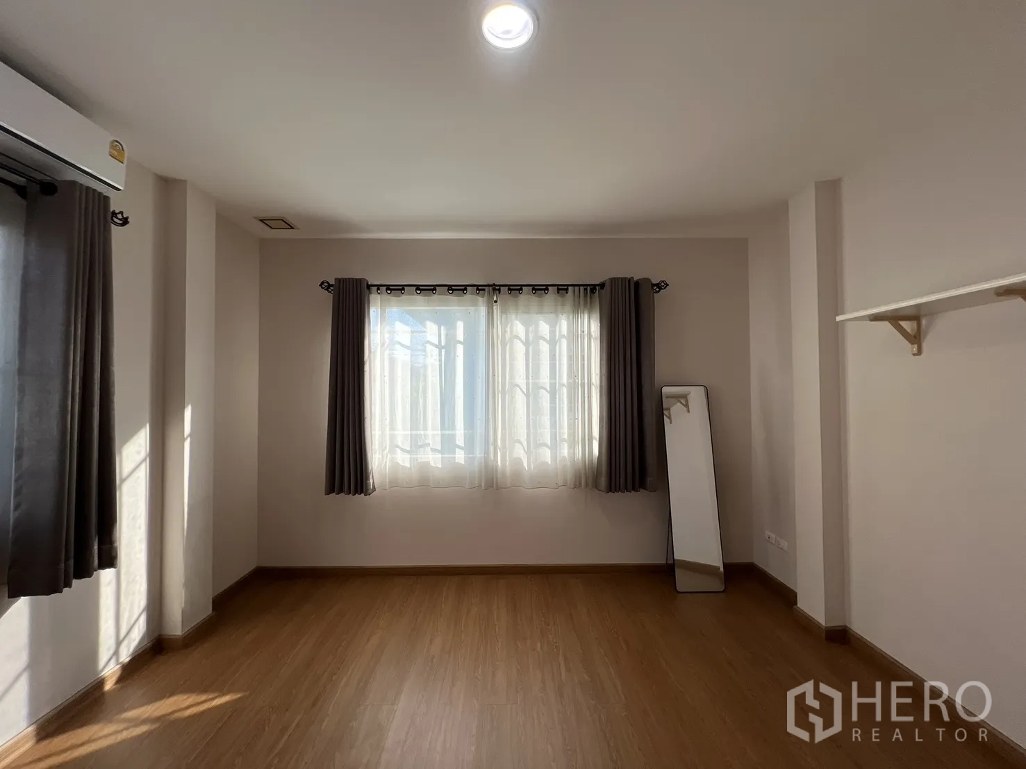 Detached House for rent in Bang Kapi, Bangkok - Bright empty room with curtains, window, and a free-standing mirror.