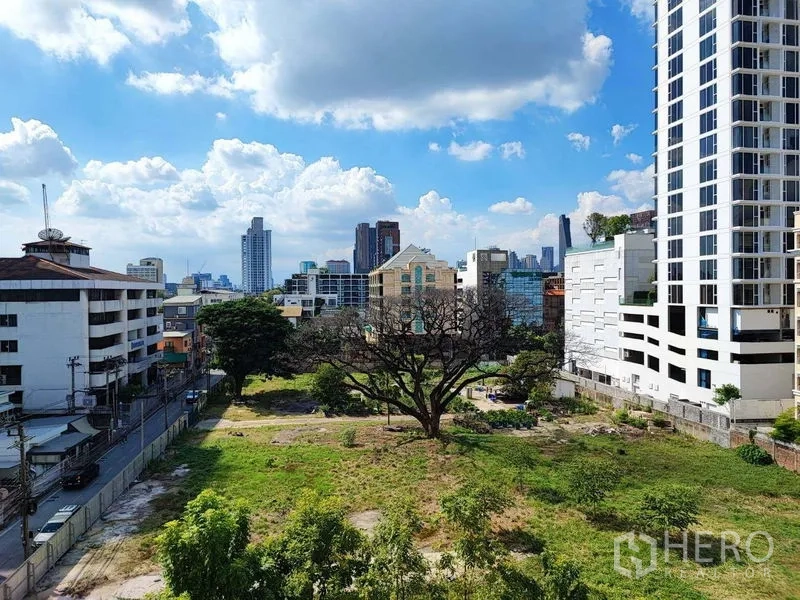 Condominium for sale in Khlong Toei, Bangkok - City skyline view over a green open space with a large tree and surrounding high-rises.