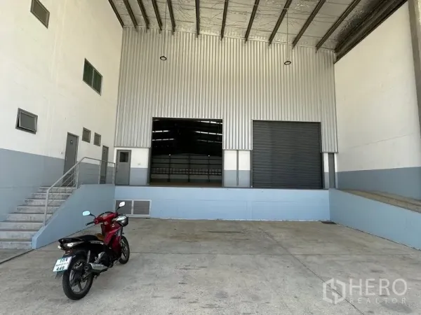 Factory for rent in Mueang Samut Prakan, Samut Prakan - Covered loading dock with roller shutter doors and side staircase to office area.