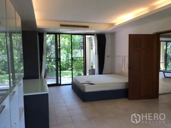 บ้าน ให้เช่าในWatthana, Bangkok - ห้องนอนชั้นล่างเปิดออกสู่สวนด้วยประตูกระจกบานเลื่อน พื้นกระเบื้องและตู้เก็บของ.