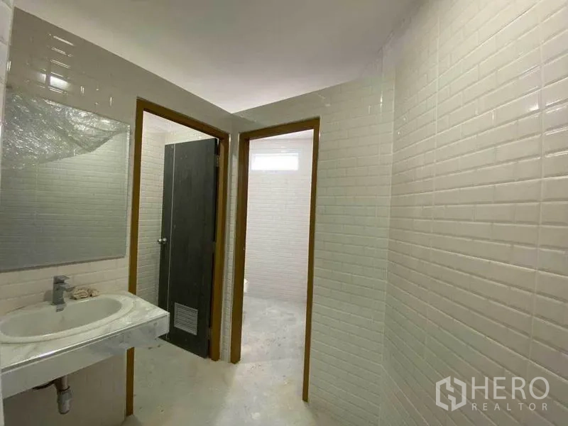 Retail Space for rent in Khlong Toei, Bangkok - Clean tiled restroom with basin and separate cubicles.