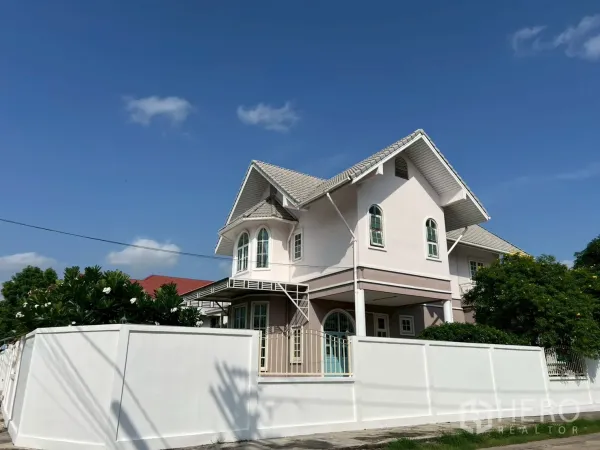 独立式住宅 出售在Phra Khanong, Bangkok - 街角视角的围墙独栋两层房，山墙屋顶与拱窗。