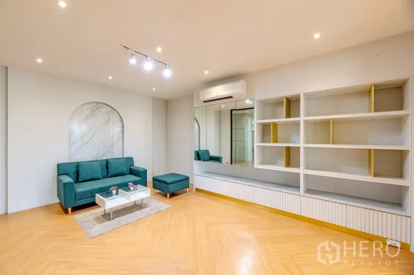 Office Space for rent in Wang Thonglang, Bangkok - Furnished lounge area with teal sofa, built-in shelving and herringbone wood floors.