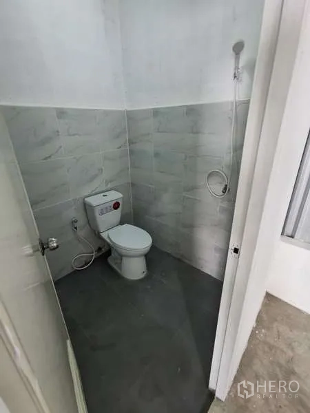 Warehouse for rent in Prawet, Bangkok - Clean restroom with toilet, handheld shower and tiled walls.