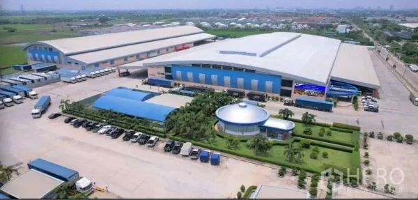 Warehouse for rent in Mueang Pathum Thani, Pathum Thani - Another aerial of the expansive warehouse complex with a round office building and landscaped parking.