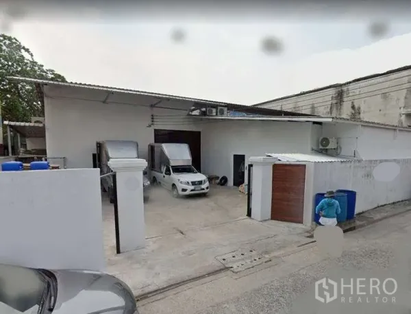 คลังสินค้า ให้เช่าหรือขายในMin Buri, Bangkok - ด้านหน้าโกดังชั้นเดียวสีขาวย่านมีนบุรี พร้อมประตูม้วน ลานคอนกรีต และที่จอดรถขนส่ง