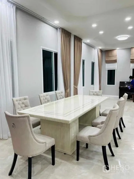 Warehouse for rent or sale in Pathum Thani - Dining room with a long marble table and upholstered chairs.