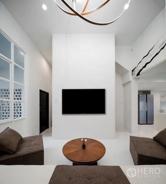 Townhouse for sale - Minimalist lounge with wall-mounted TV, sculptural chandelier and clean white walls.