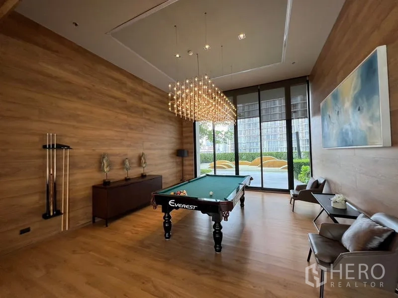 Condominium for sale - Lounge with billiards table under a statement chandelier, wood walls and garden outlook.