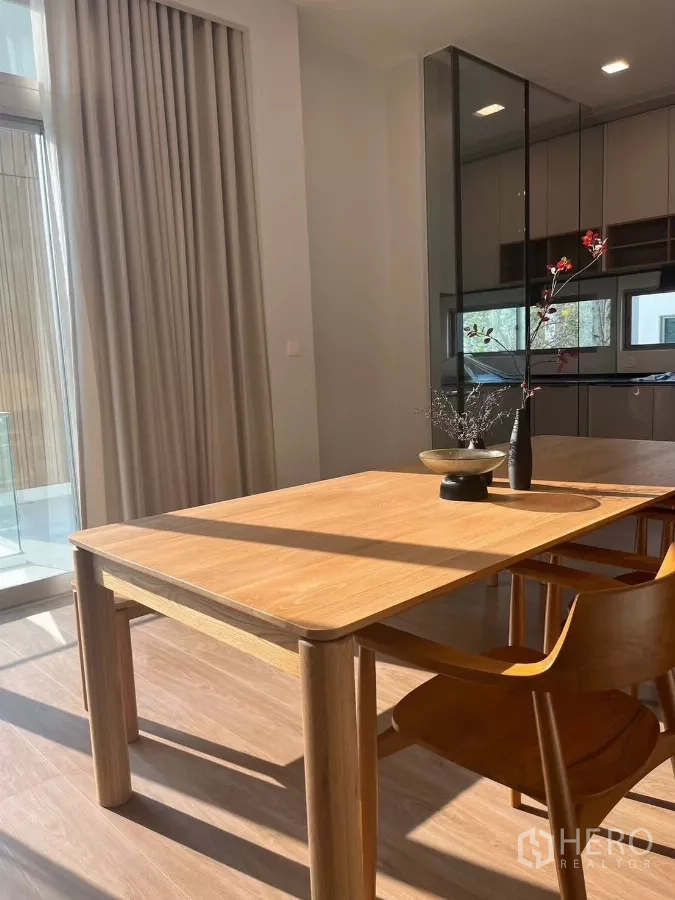 Detached House for rent in Saphan Sung, Bangkok - Sunlit dining corner with minimalist wooden table and chairs beside a glass partition.