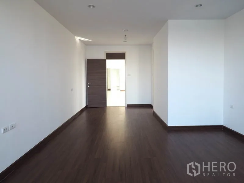 公寓 出租在Yan Nawa, Bangkok - 宽敞卧室，木地板、白墙，门通走廊。