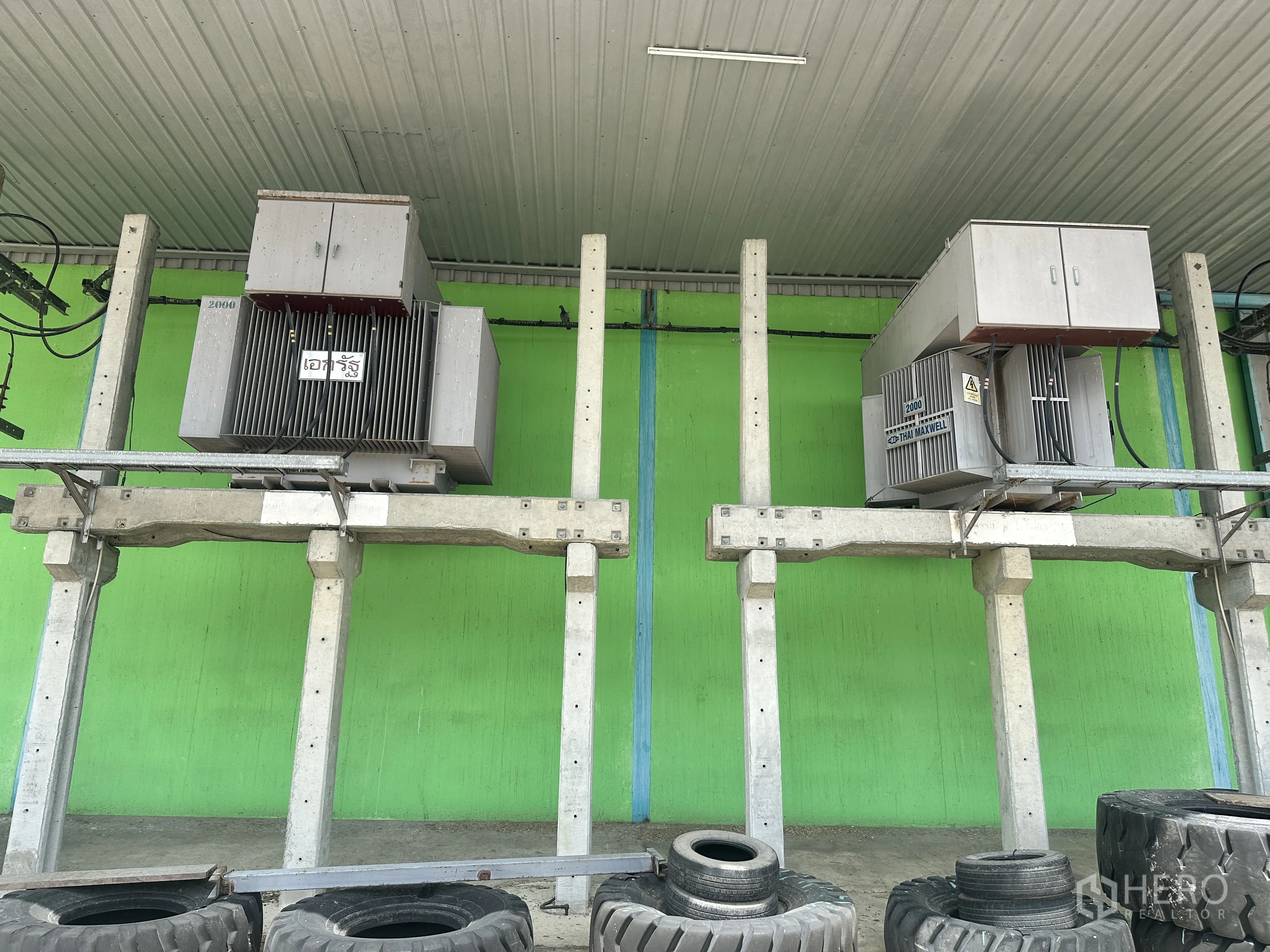 Warehouse for rent in Sai Noi, Nonthaburi - Close-up of two electrical transformers mounted on raised supports outside the warehouse.