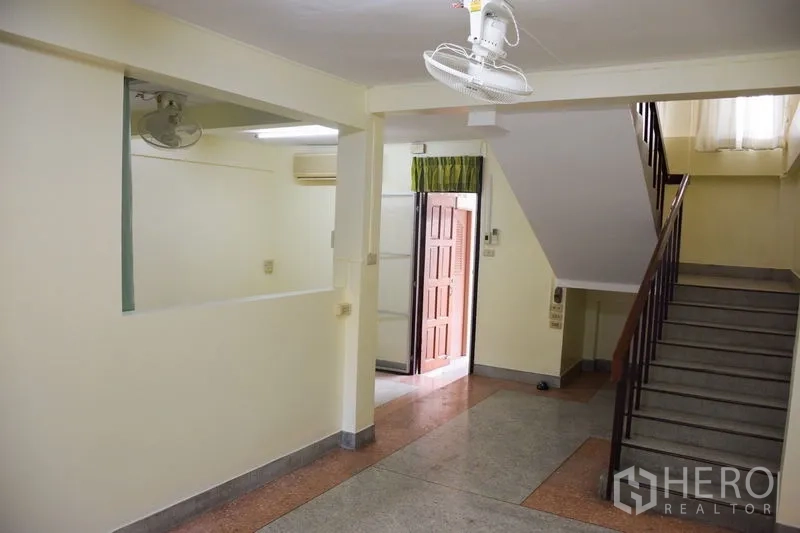 Townhouse for rent in Watthana, Bangkok - Ground-floor hall with ceiling fan and an internal staircase.