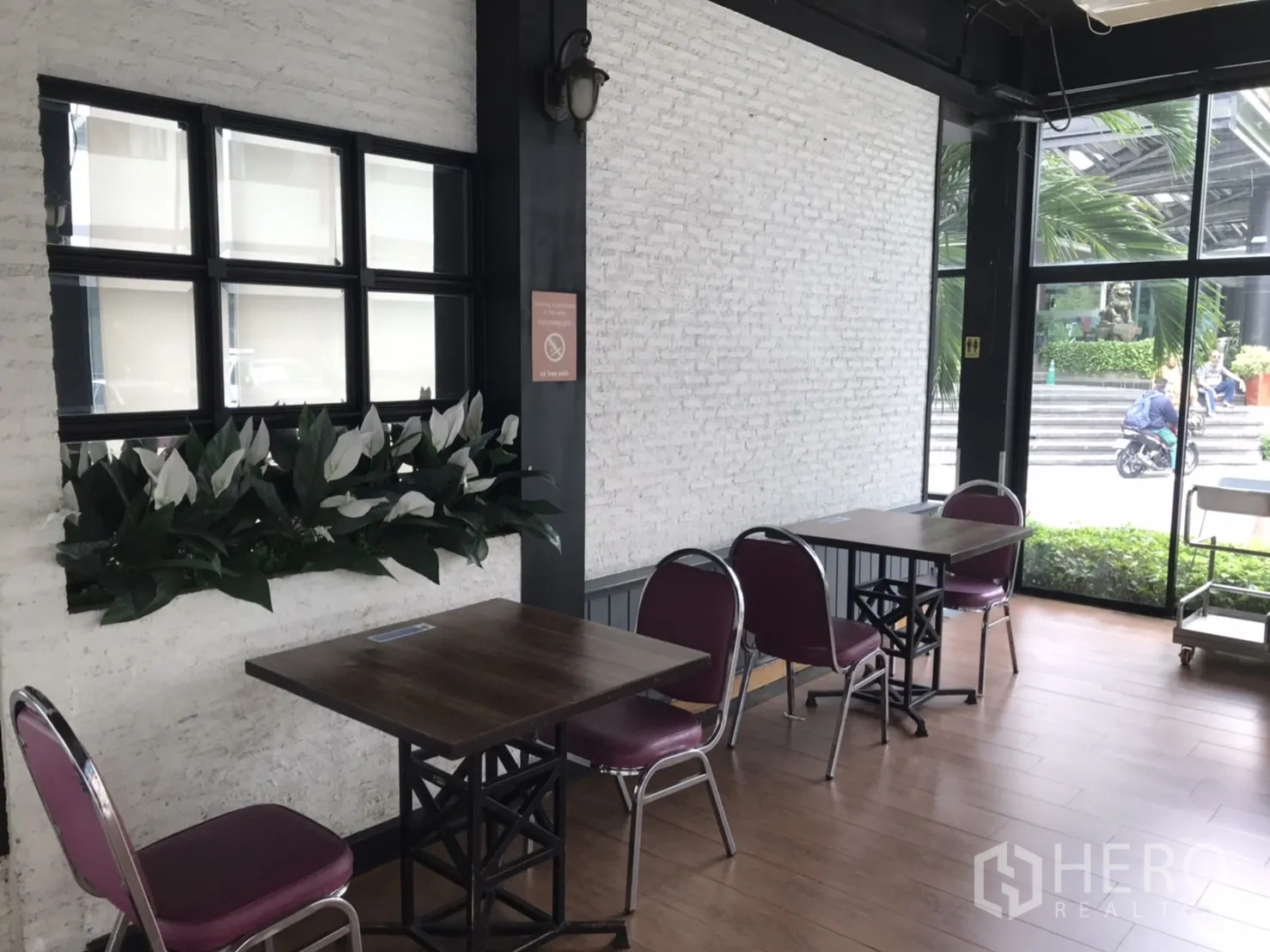Retail Space for rent in Khlong Toei, Bangkok - Seating corner with white brick wall, planter and small tables beside large windows.
