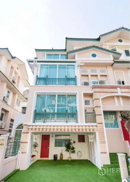Townhouse for rent in Lat Phrao, Bangkok - Four-storey Crystal Ville townhouse facade with green lawn, balconies and large windows in Lat Phrao.