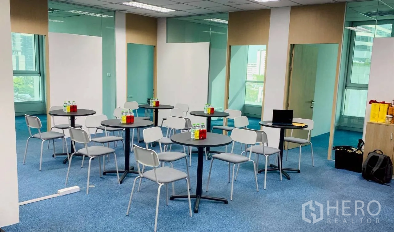 办公室 for rent in Sathon, Bangkok - 开放式办公区，圆桌与椅子、蓝色地毯及玻璃隔断。