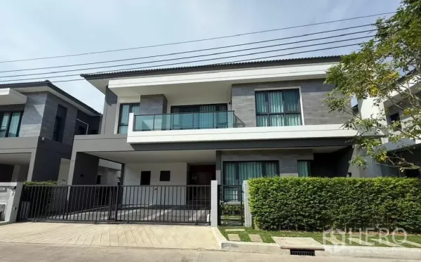 独立式住宅 出租在Bang Phli, Samut Prakan - The City Bangna 现代两层独栋别墅，带围栏车道与修剪整齐的绿篱。